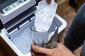 Person cleaning the interior of an ice maker with a cloth